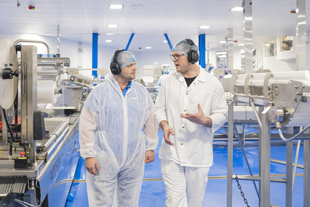 Two employees walk and talk together inside the factory